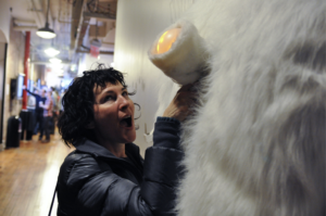 Photo of a woman touching a furry sculpture on a wall. Her action is unclear.